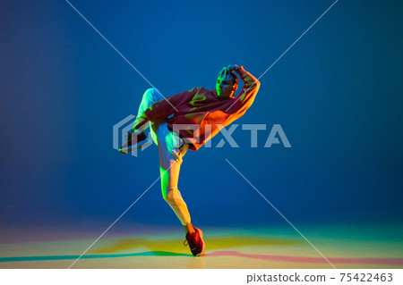 Young male dancer dancing hip-hop isolated over blue background in neon light Young male dancer dancing hip-hop isolated over blue background in neon light 75422463