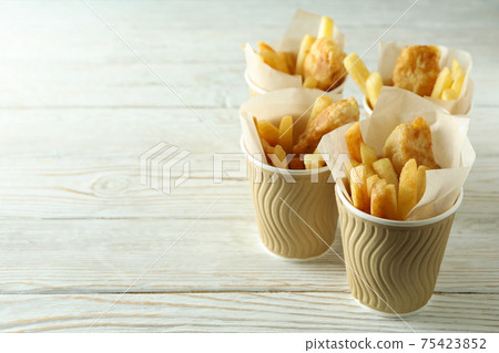 Paper cups with fried fish and chips on wooden background Paper cups with fried fish and chips on wooden background 75423852