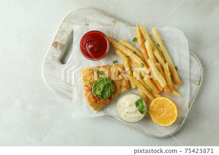 Concept of tasty eating with fried fish and chips on white textured background Concept of tasty eating with fried fish and chips on white textured background 75423871