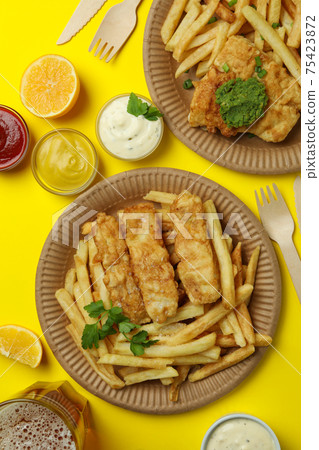Concept of tasty eating with fried fish and chips on yellow background 75423872