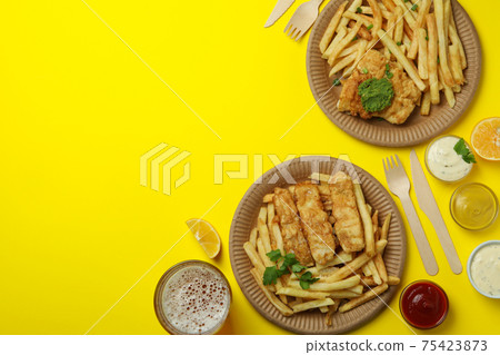 Concept of tasty eating with fried fish and chips on yellow background Concept of tasty eating with fried fish and chips on yellow background 75423873