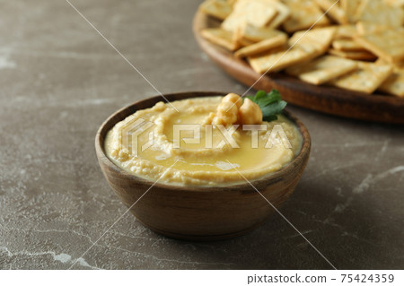 Tray with crackers and bowl of hummus on gray background 75424359