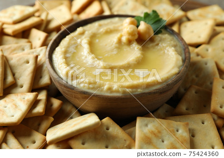 Bowl of hummus on crackers background, close up 75424360
