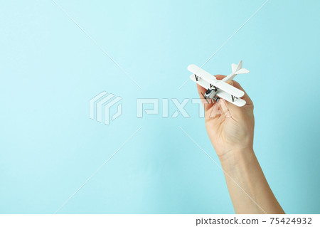 Female hand hold toy plane on blue background 75424932