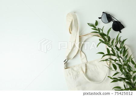 Blank textile bag, branch and sunglasses on white background 75425012