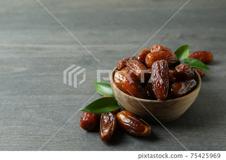 Bowl of dried dates on gray textured background Bowl of dried dates on gray textured background 75425969