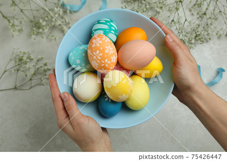 Female hands hold plate of colorful Easter eggs, top view Female hands hold plate of colorful Easter eggs, top view 75426447