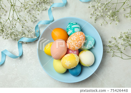 Plate with colorful Easter eggs, ribbon and gypsophila flowers on white textured background Plate with colorful Easter eggs, ribbon and gypsophila flowers on white textured background 75426448