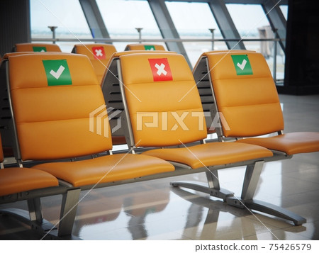 social distancing signs on soft luxury leather upholstery seats in empty airport passenger's waiting room selective focus on the signs with soft blur lonesome background in COVID-19 pandemic era 75426579