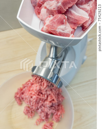 Meat grinder grinds pork meat 75429213