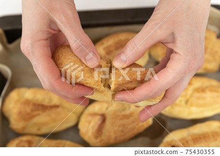 Middle of workpiece for profiteroles in hands of Chef. Puffs, popovers, eclair. Close up. 75430355