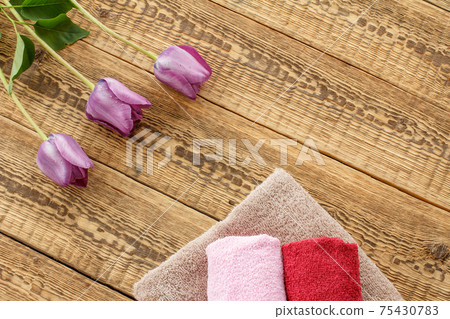 Towels and lilac tulip flowers on wooden background. Towels and lilac tulip flowers on wooden background. 75430783