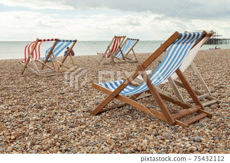 Empty red and blue striped deck chairs in Brigthon, UK. Empty red and blue striped deck chairs in Brigthon, UK. 75432112