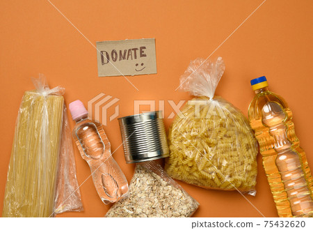 inscription on the cardboard donate and various products, fruits, pasta, sunflower oil in a plastic bottle inscription on the cardboard donate and various products, fruits, pasta, sunflower oil in a plastic bottle 75432620