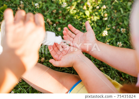 Life during coronavirus pandemic. Mother and daughter disinfecting hands with sanitizer outdoors in city park, summer hygiene healthcare concept, lifestyle, selective focus, antibacterial antiseptic Life during coronavirus pandemic. Mother and daughter disinfecting hands with sanitizer outdoors in city park, summer hygiene healthcare concept, lifestyle, selective focus, antibacterial antiseptic 75435824
