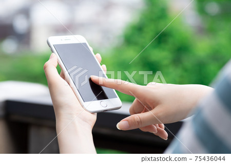 Woman operating a smartphone 75436044