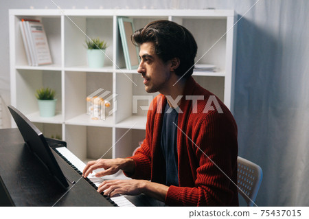 Talented young musician man playing piano at home studio during lesson in free time. 75437015