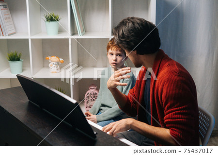 Caucasian boy playing synthesizer at home during lesson. Concept of music education. 75437017