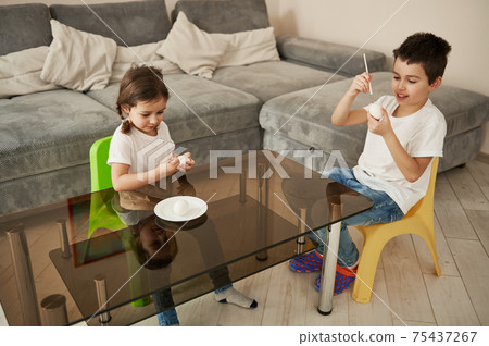 Children, boy and girl, coloring Easter eggs at home. High angle view Children, boy and girl, coloring Easter eggs at home. High angle view 75437267