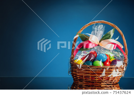Easter gift basket with multicolor eggs, blue background with copy-space Easter gift basket with multicolor eggs, blue background with copy-space 75437624