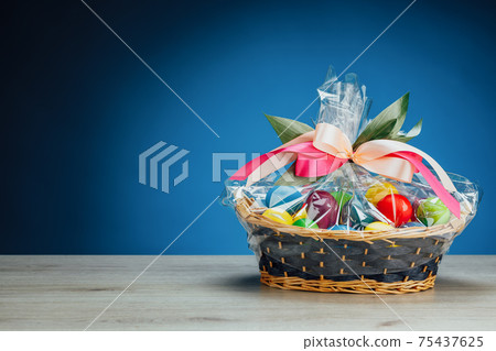 Easter gift basket with multicolor eggs, blue background Easter gift basket with multicolor eggs, blue background 75437625