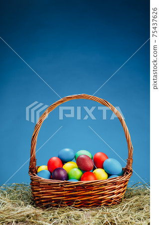 Easter basket with multicolor eggs, blue background Easter basket with multicolor eggs, blue background 75437626