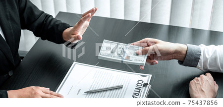 Business woman refusing receive bribe money in the envelope of their partner to give success the deal contract in a corruption scam, illegal and dishonest 75437856