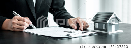 Real estate agent working sign agreement document contract for home loan insurance approving purchases for client with house model and key on table Real estate agent working sign agreement document contract for home loan insurance approving purchases for client with house model and key on table 75437860