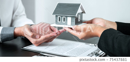Sale Estate agent giving house model to new client after signing agreement contract with approved property form, Home Insurance and Real estate investment concept 75437881