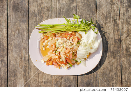 Papaya salad with pink plates placed on a wooden table. Papaya salad with pink plates placed on a wooden table. 75438007