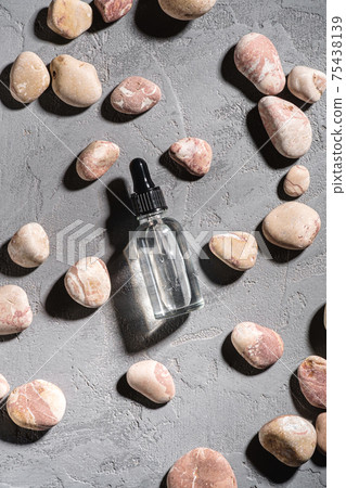 Skin care essence oil dropper in glass bottle near to pebbles Skin care essence oil dropper in glass bottle near to pebbles 75438139
