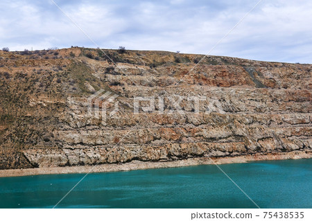 section of an old limestone quarry with a blue lake at the bottom section of an old limestone quarry with a blue lake at the bottom 75438535