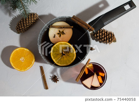 Glintwein in a glass and a ladle with cinnamon, apple, badyan, cloves.  75440058