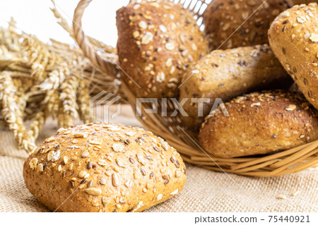 Rye bread. Bakery with crusty loaves and crumbs. Fresh loaf of rustic traditional bread with wheat grain ear or rye spike plant on natural cotton background. Healthy Food concept. Rye bread. Bakery with crusty loaves and crumbs. Fresh loaf of rustic traditional bread with wheat grain ear or rye spike plant on natural cotton background. Healthy Food concept. 75440921