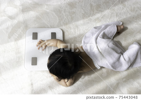 Image of weight measurement. Baby and scale (8 months old, girl) 75443048