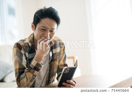 A man looking at a smartphone with a smile 75445664