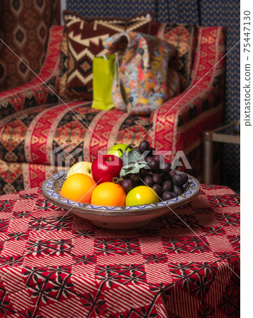 Apples, oranges and grapes in a plate on the table Apples, oranges and grapes in a plate on the table 75447130