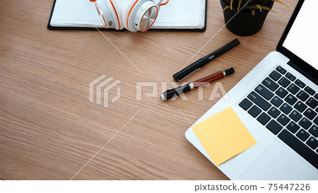 Computer laptop, pens, head phone and notebook on wooden office desk. Computer laptop, pens, head phone and notebook on wooden office desk. 75447226
