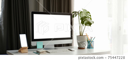Mock up computer and smart phone on white table at contemporary workplace. Blank screen for advertising text. 75447228