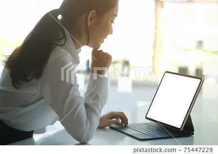 Side view of beautiful woman office worker working with computer tablet at office desk. Side view of beautiful woman office worker working with computer tablet at office desk. 75447229