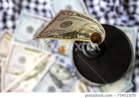 Barrel of oil on a background, american dollars and arabian background. Falling trend of barrel price decrease of earning and global economics . Selective focus. 75451870