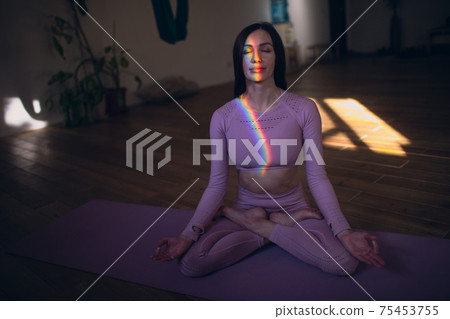 Woman practicing meditation and yoga with rainbow light on her body and face Woman practicing meditation and yoga with rainbow light on her body and face 75453755