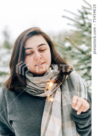 Adult young woman with sparklers on the background of winter pine forest Adult young woman with sparklers on the background of winter pine forest 75454619