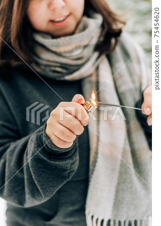 Adult young woman with sparklers on the background of winter pine forest 75454620