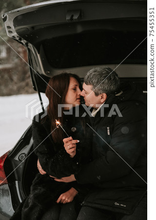 A man and a woman on the background of a snow-covered forest in a snowfall in the trunk of a car A man and a woman on the background of a snow-covered forest in a snowfall in the trunk of a car 75455351