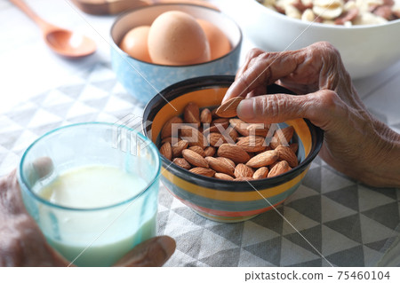 close up senior women hand picking almond nut from a bowl close up senior women hand picking almond nut from a bowl 75460104
