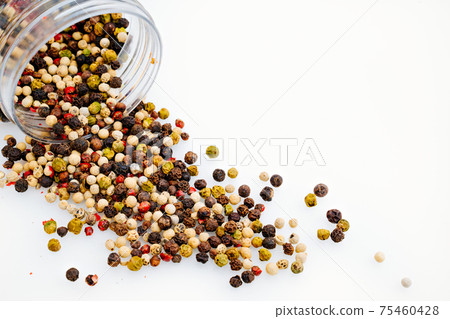 a mixture of peppers is scattered from a jar on a white background. 75460428