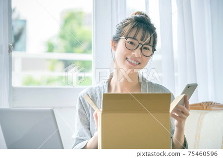 A woman in young pajamas with a smartphone checking her luggage at home 75460596