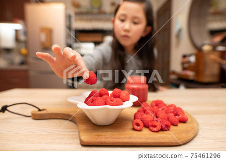 Girl picking up raspberries 75461296
