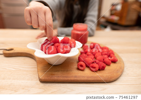 Girl picking up raspberries 75461297